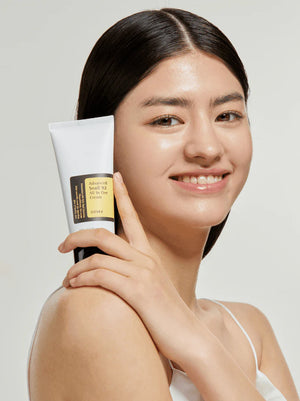 Woman holding a skincare product with a plain background