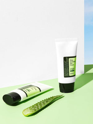 Two tubes of aloe vera cream on a green surface with aloe leaves, against a white and blue gradient background.